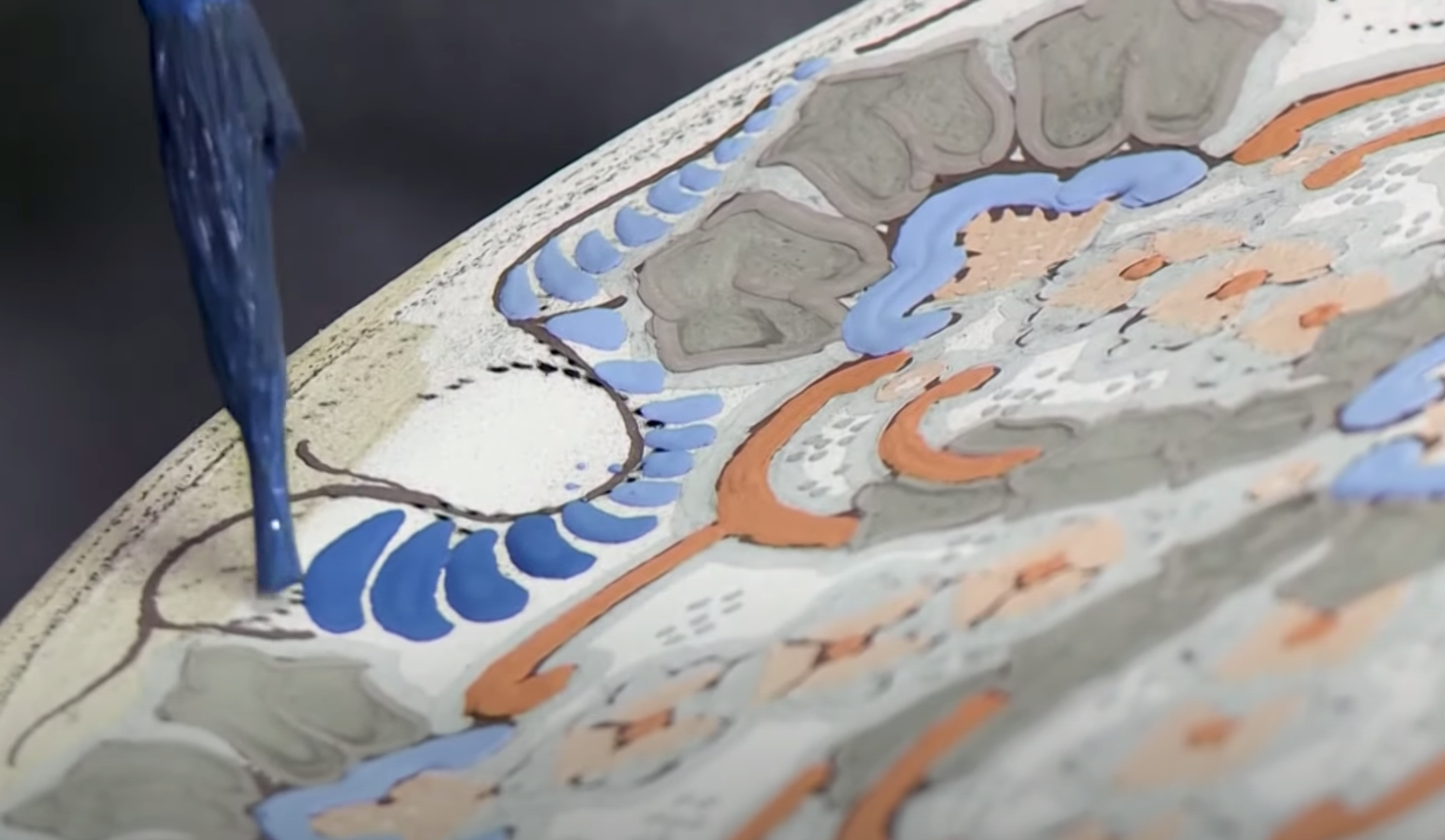 A piece of Talavera pottery being painted in blue